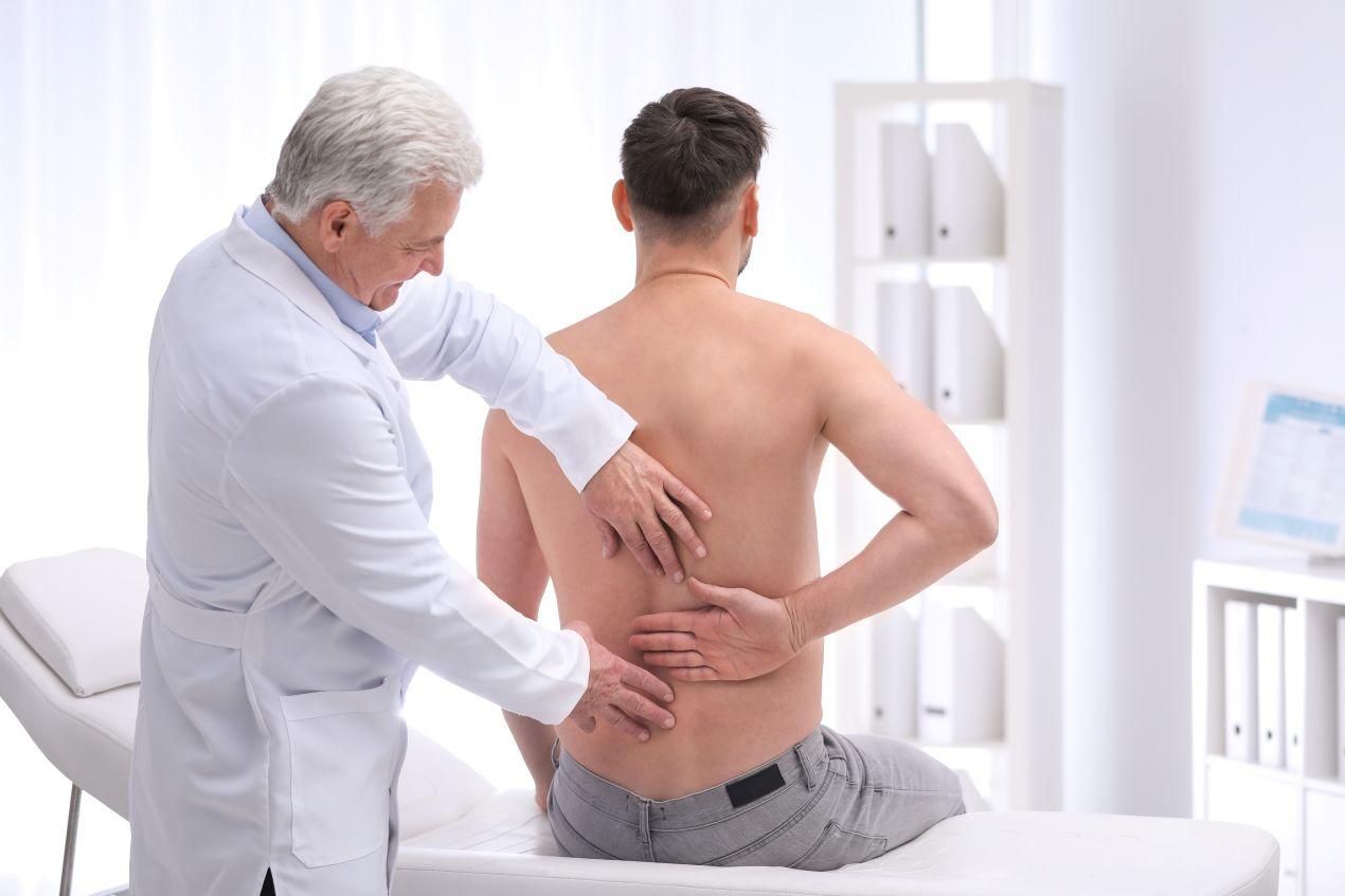 Arzt untersucht Rücken eines Patienten – typischer Besuch beim Erlangen Orthopäde zur Schmerzanalyse.