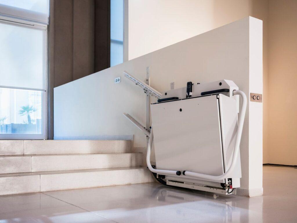 Treppenlift mit Plattform an einer Innentreppe in eingefahrener Position, platzsparend montiert