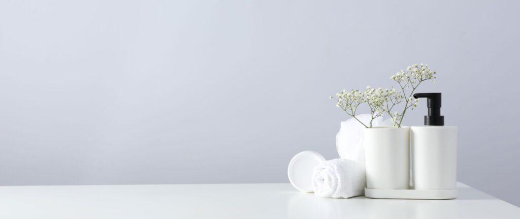 Minimalistische Badezimmerdekoration mit Spender, Handtuch und Blumen – symbolisiert das stilvolle Umfeld moderner Duschtoiletten