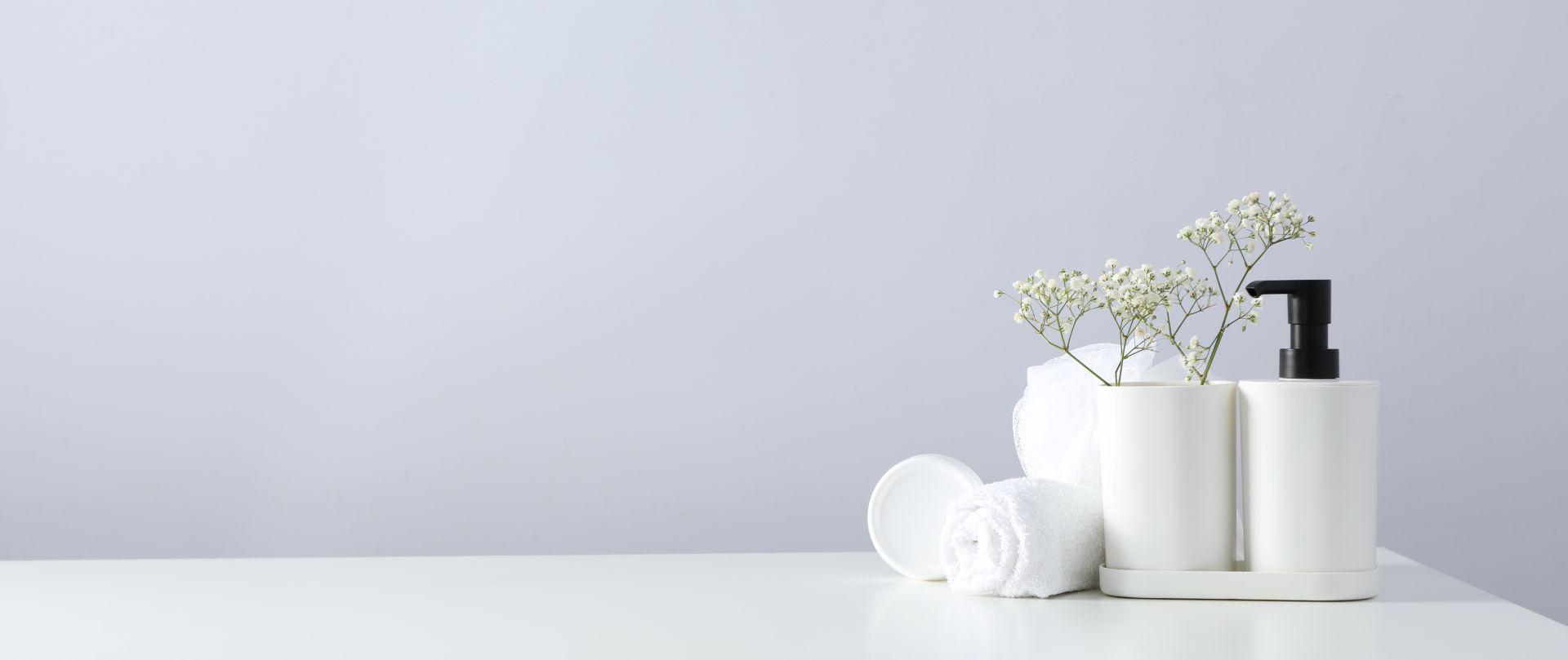 Minimalistische Badezimmerdekoration mit Spender, Handtuch und Blumen – symbolisiert das stilvolle Umfeld moderner Duschtoiletten