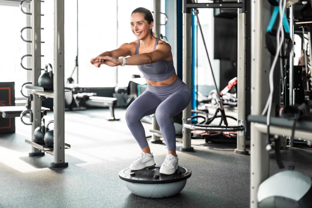 Frau trainiert auf Balanceball im Studio | Barfußschuhe