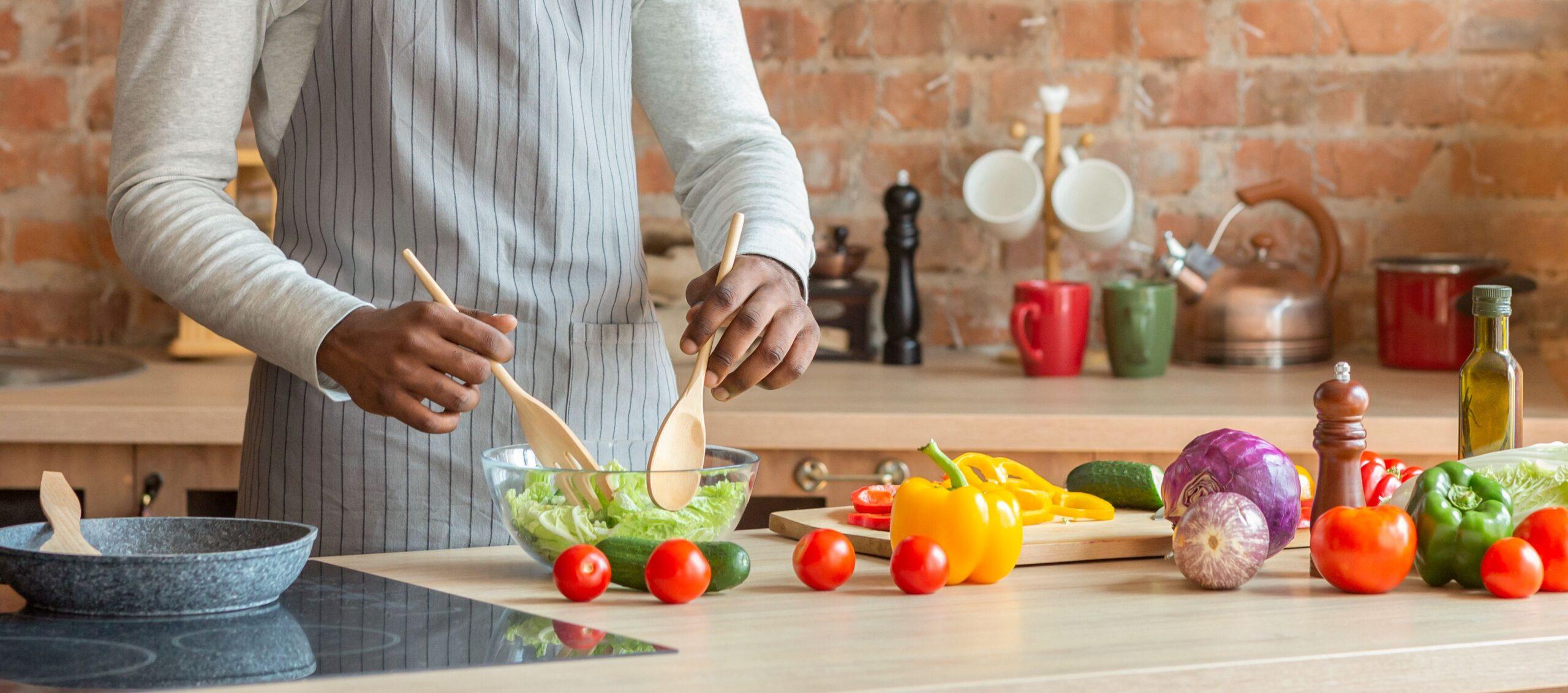 Mann, der frischen gesunden Gemüsesalat in der Küche zubereitet