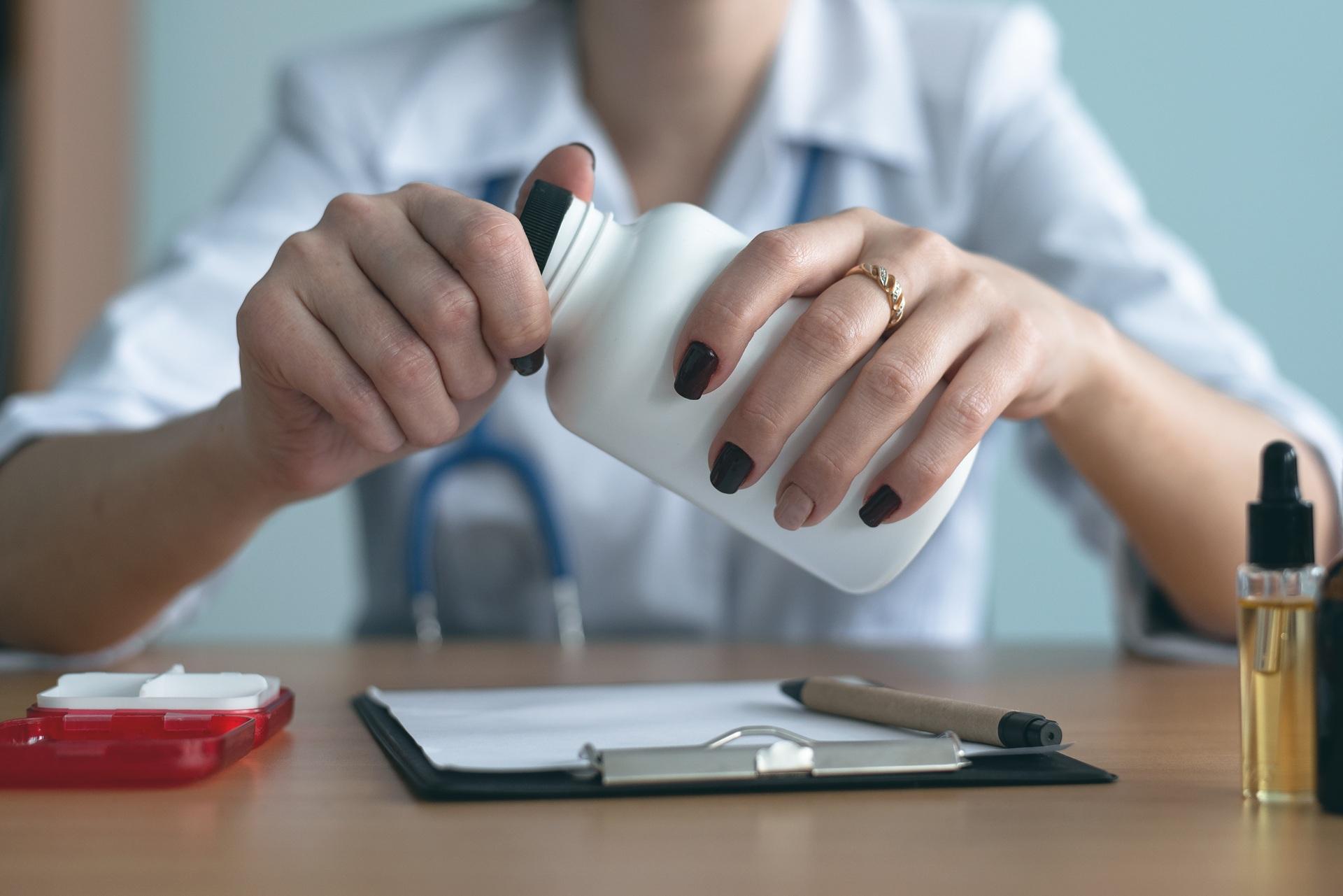 Ärztin öffnet Medikamentenflasche zur Analyse | klinische Bewertung